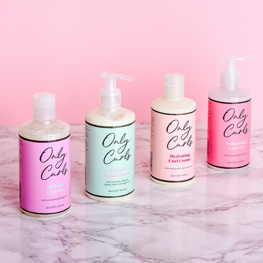 Full Size Collection of all 4 Only Curls Styling Products. Lined up on pink background on marble worktop